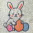 Cute Easter bunny embroidery design holding colorful eggs