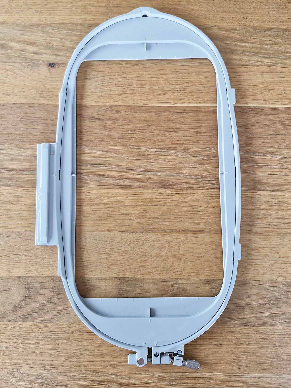 Brother 260×160 embroidery hoop frame Physical size of a Brother 260x160 embroidery hoop on a wooden surface