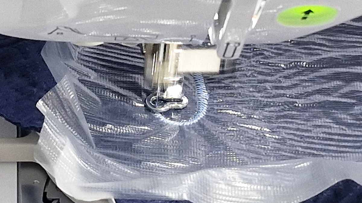 Machine embroidery in progress on muslin Embroidery machine stitching a name onto muslin fabric