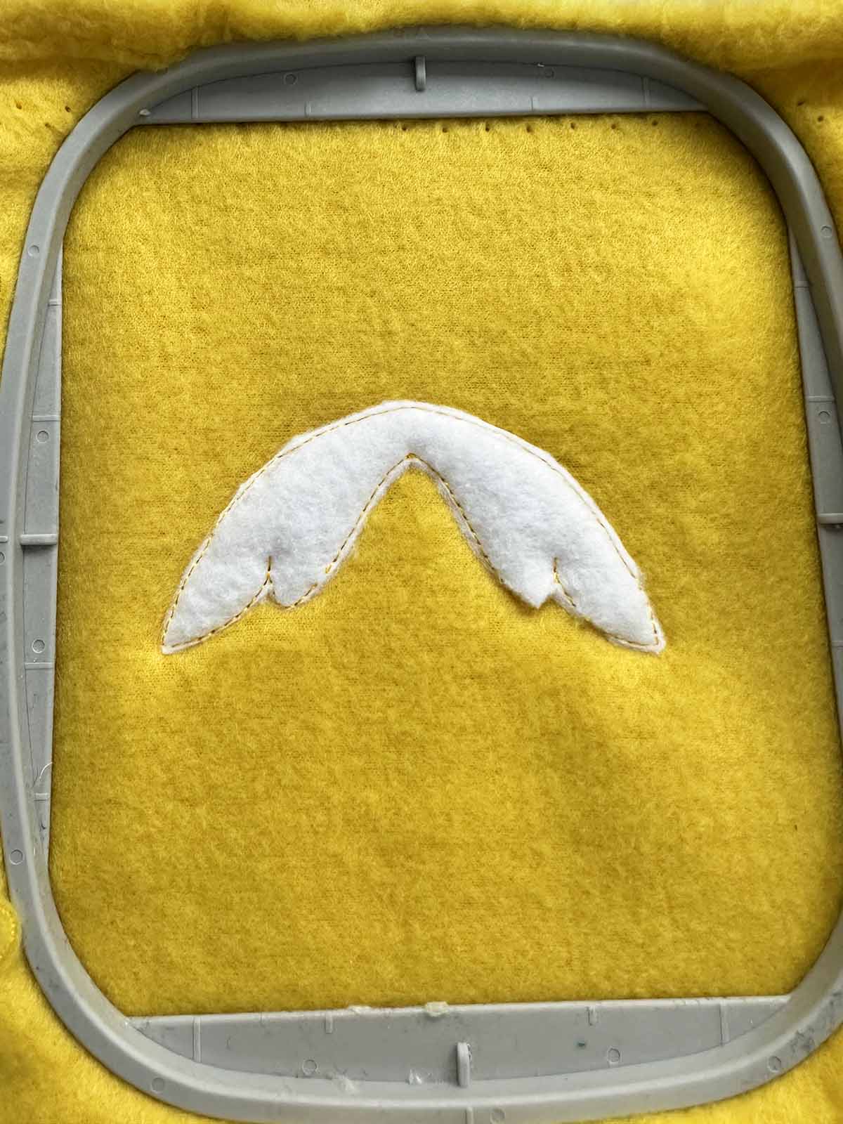 Excess stabilizer trimmed close to the stitched wing outline on yellow plush fabric