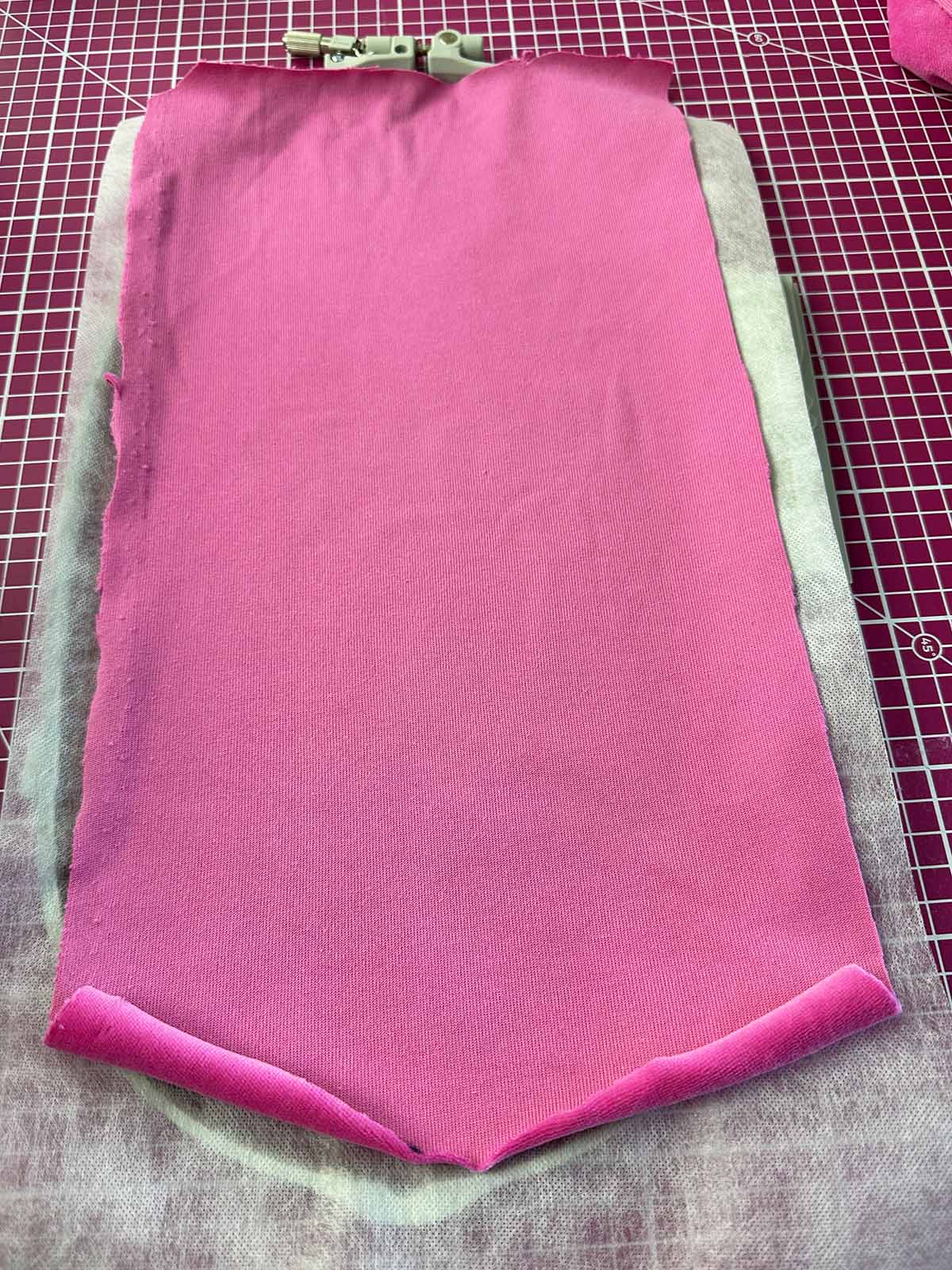 Pink plush fabric hooped with stabilizer in embroidery frame for beak and feet embroidery