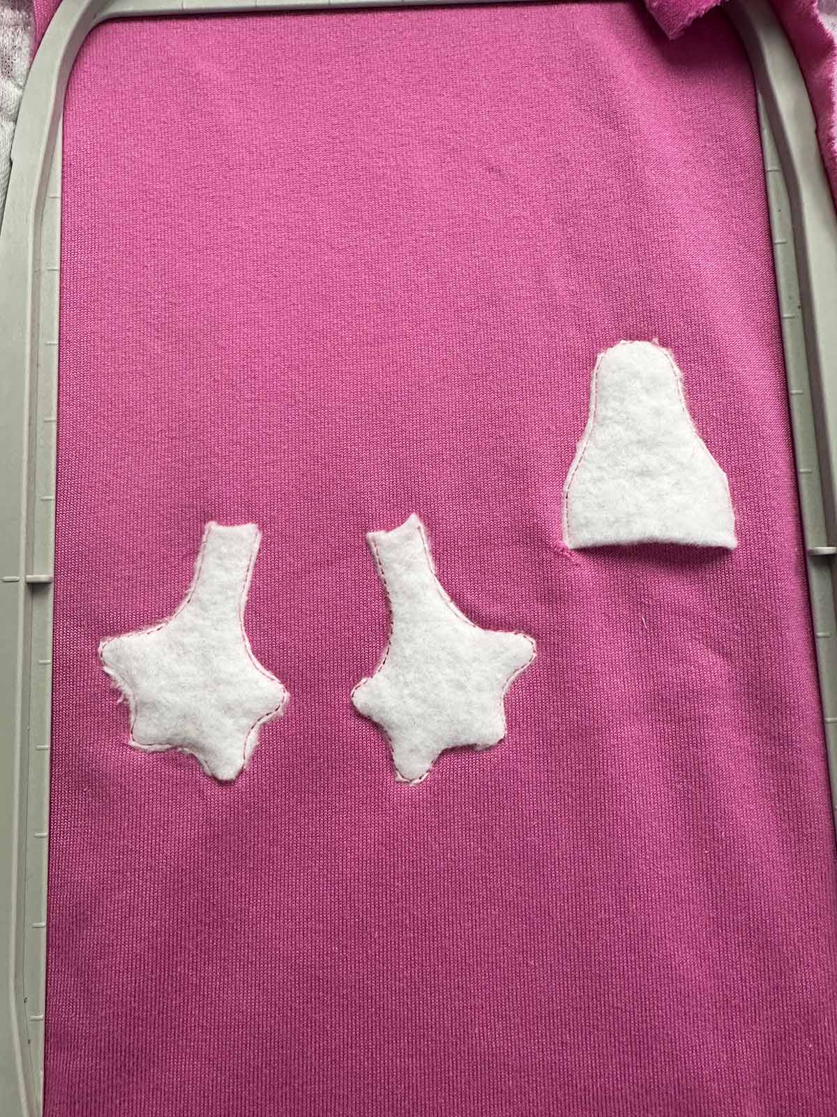 Padding layer secured onto pink plush fabric after initial stitching for beak and feet