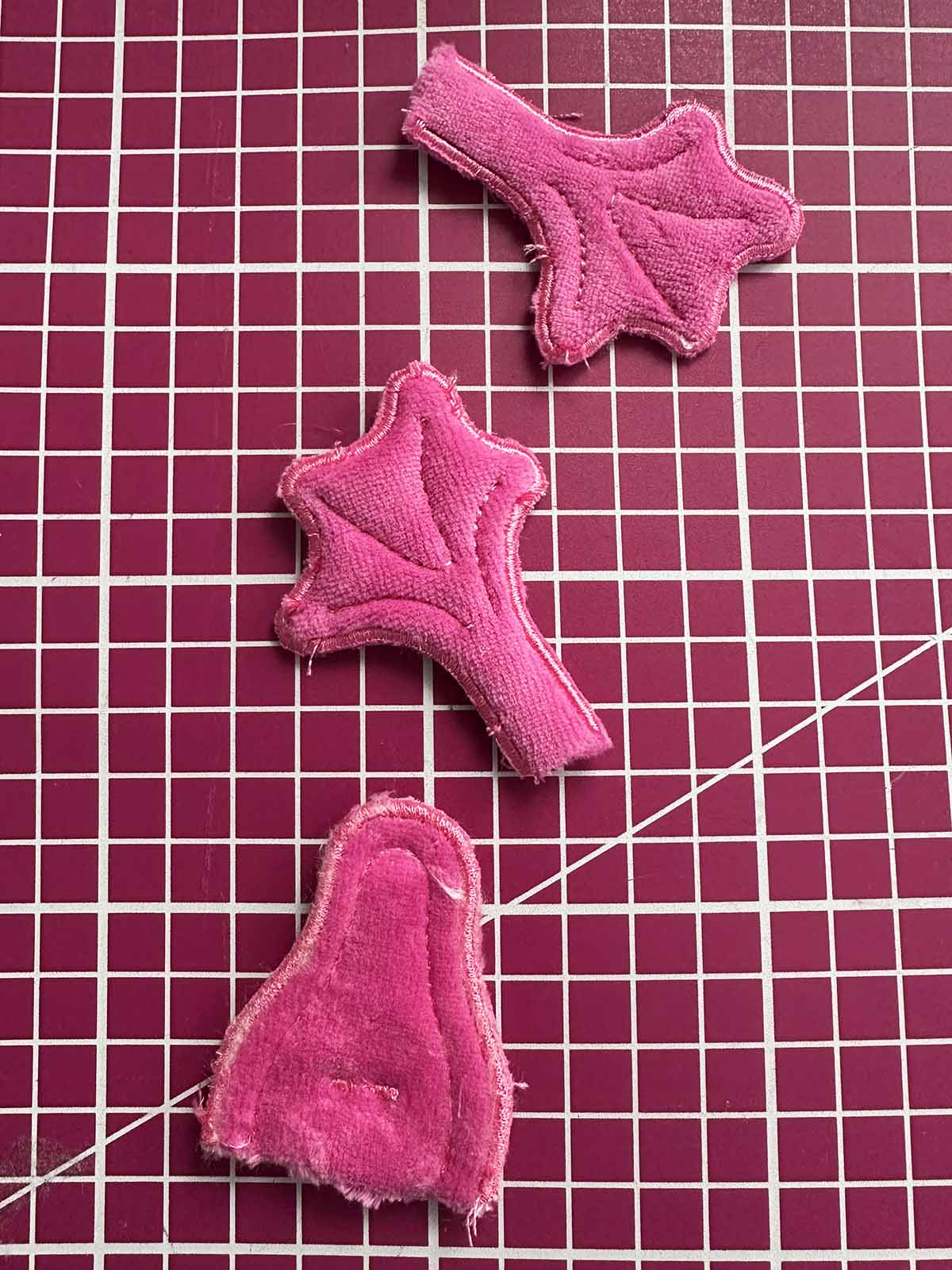 Finished beak and feet pieces cut out from pink plush fabric after embroidery