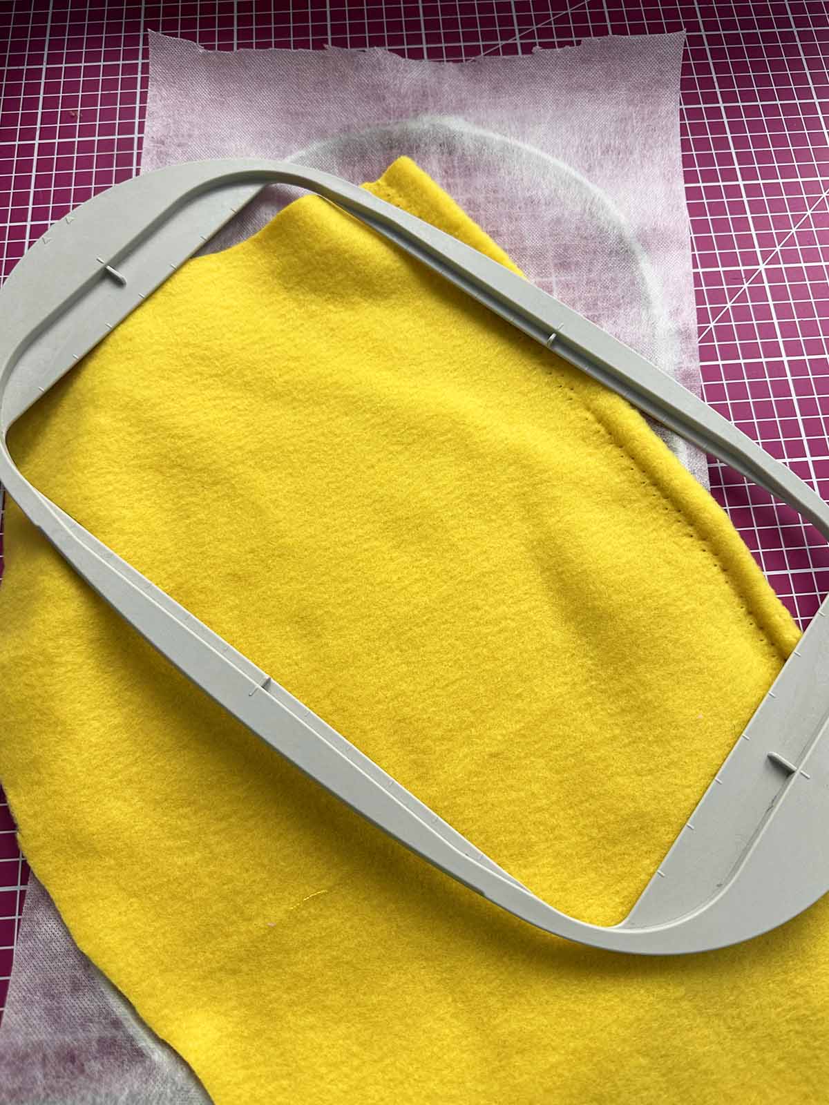 Yellow plush fabric hooped with stabilizer in embroidery hoop for duck body stitching