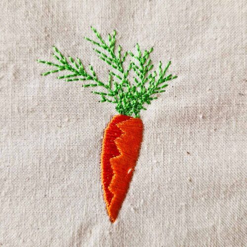 Carrot embroidery design with soft color transition and green leaves stitched on fabric