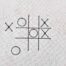 Small tic tac toe embroidery design with grid and X and O symbols stitched on fabric