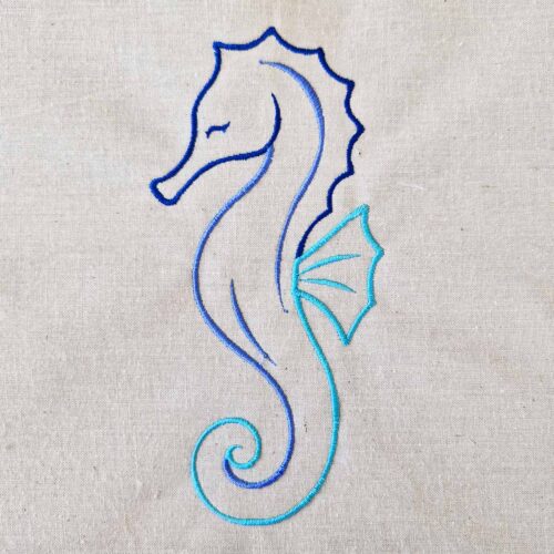 Seahorse satin line art embroidery design stitched in blue tones on cotton fabric.